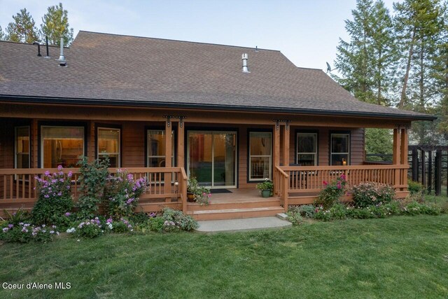 rear view of house featuring covered porch and a yard