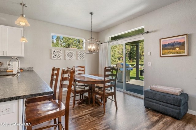 dining room with dark wood-type flooring, a notable chandelier, and sink