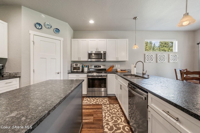 kitchen featuring white cabinets, dark hardwood / wood-style flooring, sink, decorative light fixtures, and stainless steel appliances