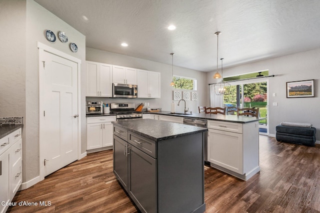 kitchen featuring white cabinetry, appliances with stainless steel finishes, decorative light fixtures, and dark wood-type flooring