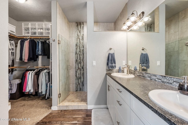 bathroom featuring a shower with door, wood-type flooring, a textured ceiling, and vanity