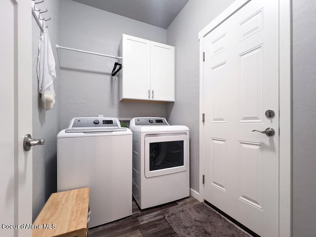 laundry area featuring dark wood-type flooring, washer and clothes dryer, and cabinets