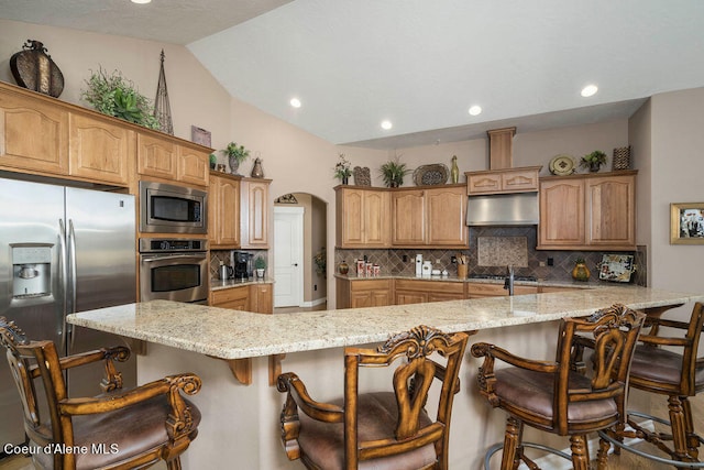 kitchen with lofted ceiling, a kitchen bar, a spacious island, and appliances with stainless steel finishes