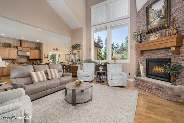 living room featuring a fireplace, light hardwood / wood-style flooring, and a high ceiling