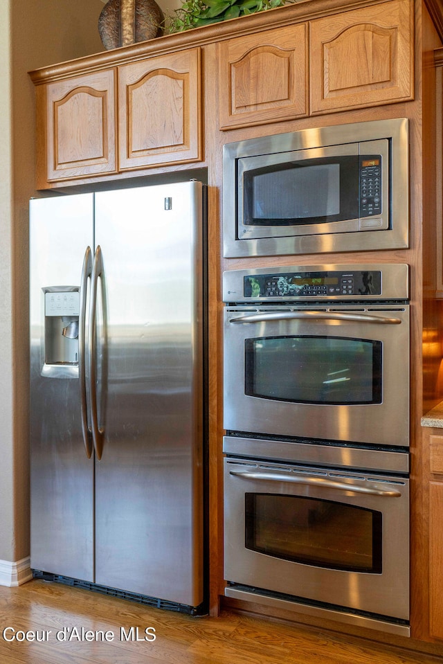 kitchen with stainless steel appliances, light brown cabinets, and light hardwood / wood-style flooring