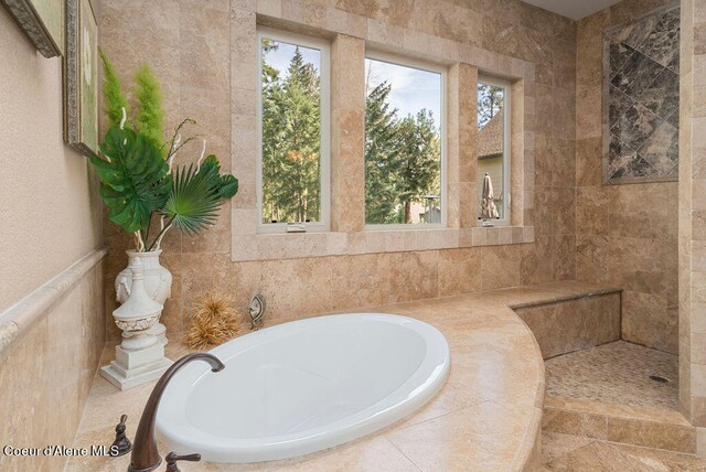 bathroom with tile walls and tiled tub