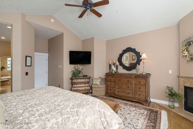 bedroom featuring hardwood / wood-style flooring, ceiling fan, ensuite bath, and lofted ceiling