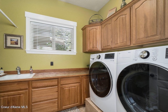 clothes washing area featuring washing machine and dryer, cabinets, and sink