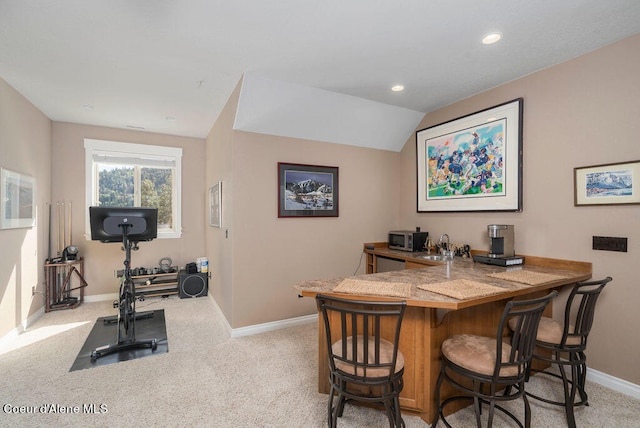 carpeted dining area with indoor wet bar and vaulted ceiling