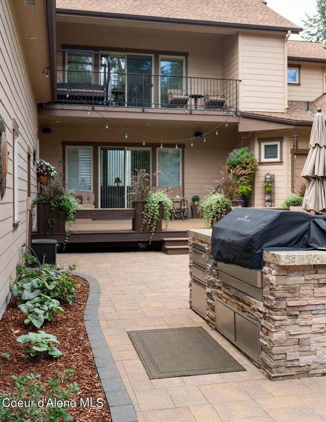 view of patio featuring area for grilling, a balcony, and exterior kitchen