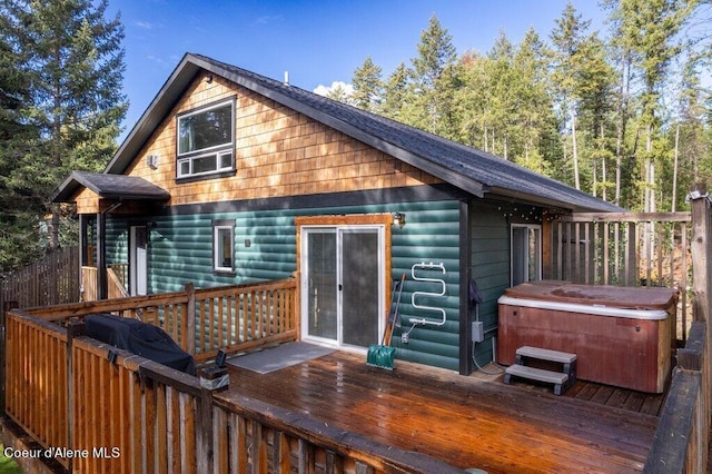 back of property with a hot tub and a wooden deck