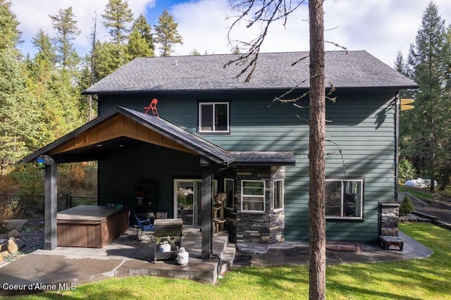 rear view of house featuring a patio, a hot tub, and a yard