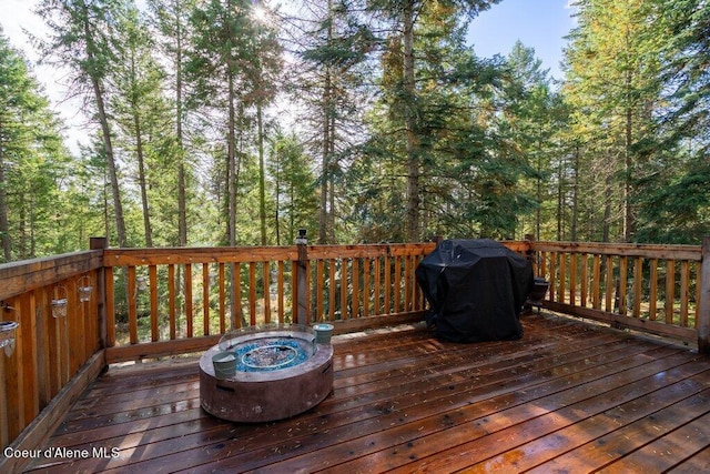 wooden terrace featuring a grill and a fire pit