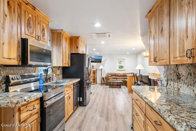 kitchen with tasteful backsplash, sink, light hardwood / wood-style floors, stainless steel appliances, and light stone counters