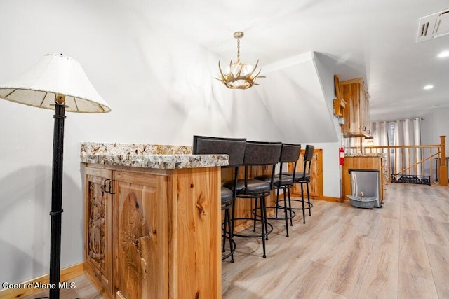 bar featuring light hardwood / wood-style flooring and a chandelier