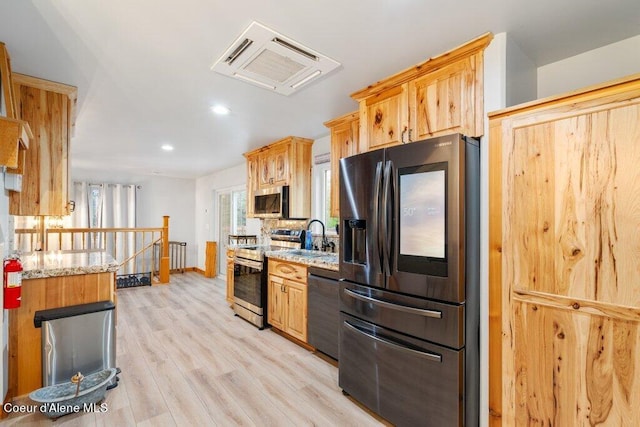 kitchen with tasteful backsplash, sink, stainless steel appliances, light stone counters, and light hardwood / wood-style flooring