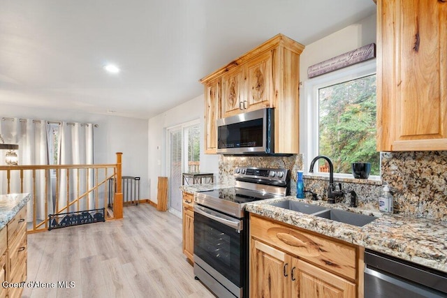 kitchen featuring appliances with stainless steel finishes, light hardwood / wood-style flooring, a healthy amount of sunlight, and sink