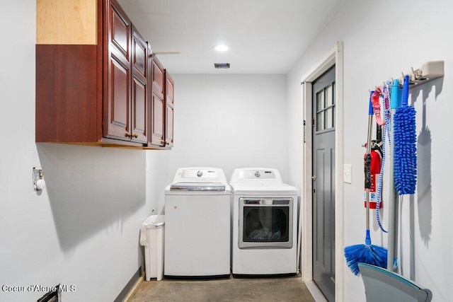 clothes washing area featuring cabinets and separate washer and dryer