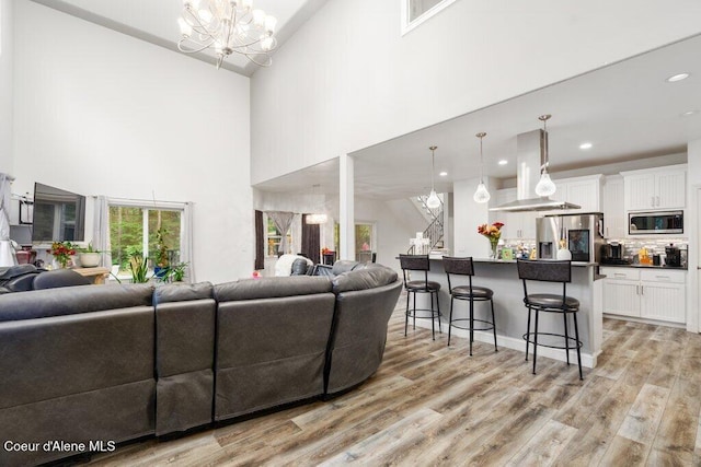 living room featuring light hardwood / wood-style floors, a notable chandelier, and high vaulted ceiling