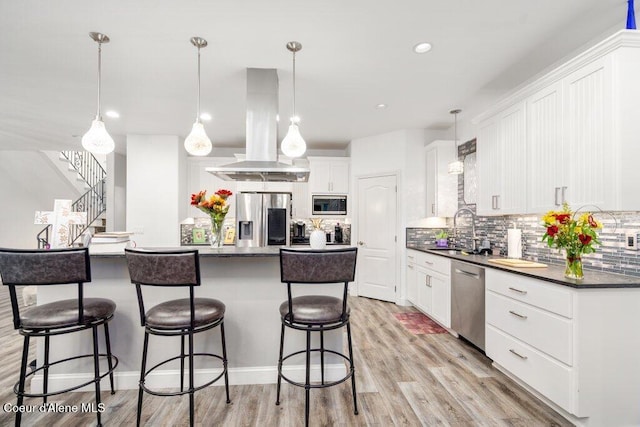 kitchen featuring island range hood, sink, a center island, white cabinetry, and appliances with stainless steel finishes