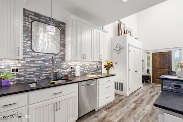 kitchen featuring white cabinets, hanging light fixtures, light wood-type flooring, dishwasher, and sink