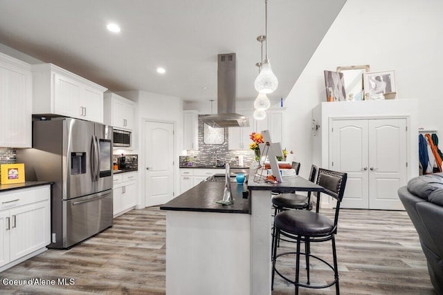 kitchen featuring white cabinetry, stainless steel appliances, hardwood / wood-style floors, and island range hood