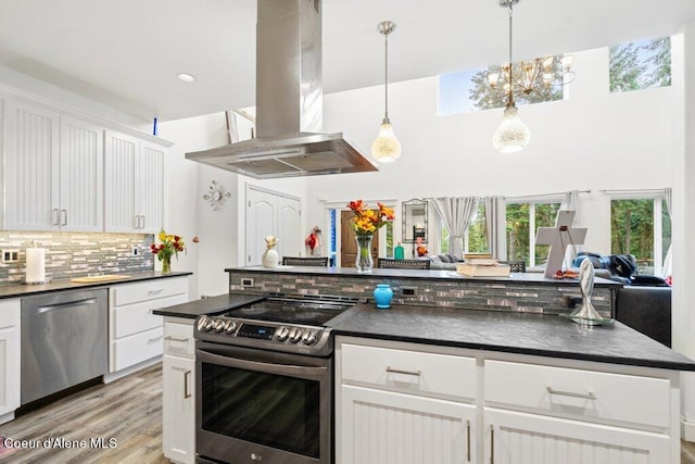 kitchen featuring island exhaust hood, stainless steel appliances, decorative light fixtures, white cabinets, and light hardwood / wood-style floors