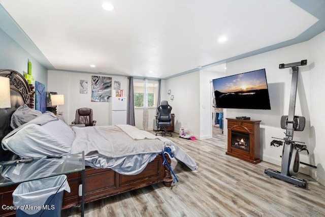 bedroom featuring white fridge and light hardwood / wood-style floors