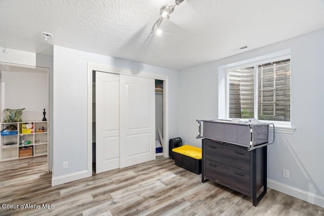 bedroom with light hardwood / wood-style flooring, a textured ceiling, and a closet