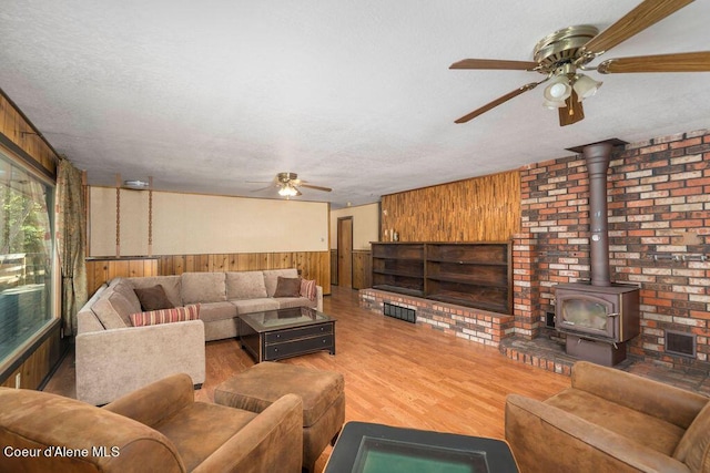 905 S Tanglewood Rd, Post Falls, ID 83854 - living area with ceiling fan, a wood stove, wood walls, wood finished floors, and wainscoting