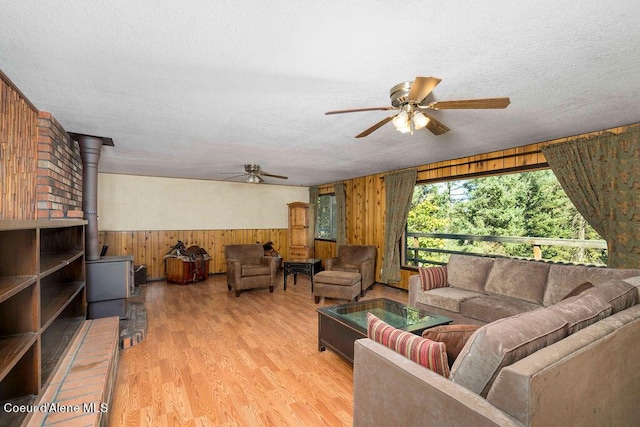 905 S Tanglewood Rd, Post Falls, ID 83854 - living room with ceiling fan, wood walls, a wood stove, light wood finished floors, and a textured ceiling