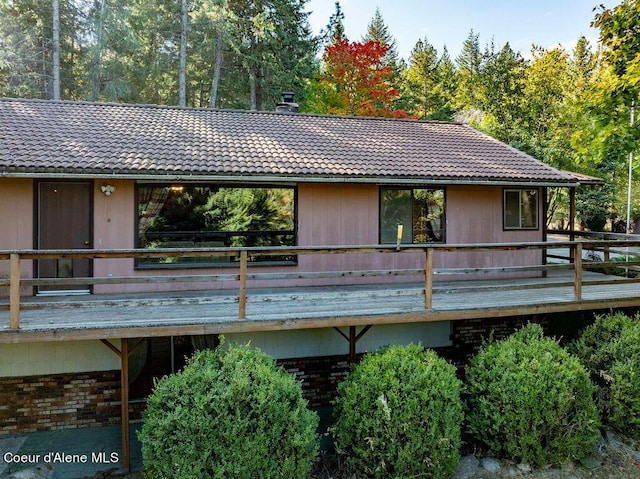 905 S Tanglewood Rd, Post Falls, ID 83854 - back of house featuring a tiled roof, a deck, brick siding, and a chimney