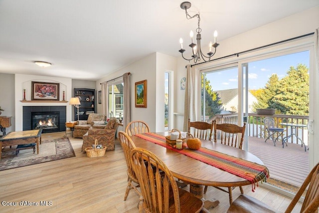 dining space featuring light hardwood / wood-style flooring, a notable chandelier, and a fireplace