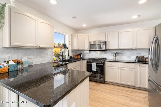 kitchen with appliances with stainless steel finishes, white cabinetry, and light hardwood / wood-style floors