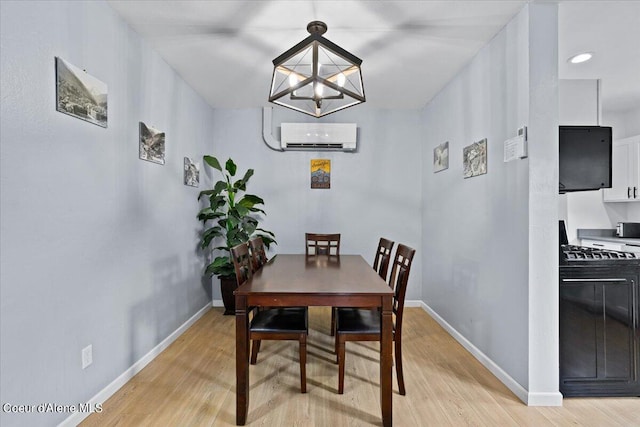 dining room with an inviting chandelier, a wall mounted AC, and light hardwood / wood-style floors