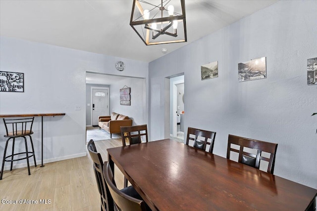 dining space with light hardwood / wood-style flooring and a notable chandelier