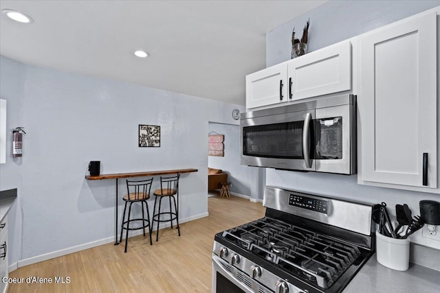 kitchen with white cabinets, light hardwood / wood-style flooring, and stainless steel appliances