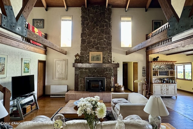 living room featuring a stone fireplace, wood ceiling, beam ceiling, wood-type flooring, and high vaulted ceiling