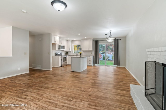 unfurnished living room with sink, hardwood / wood-style floors, and a fireplace