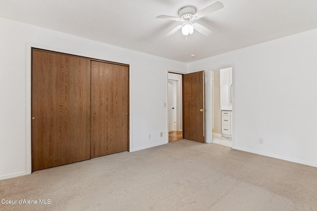 unfurnished bedroom featuring a closet, light colored carpet, connected bathroom, and ceiling fan