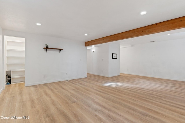 unfurnished living room with beam ceiling and light wood-type flooring