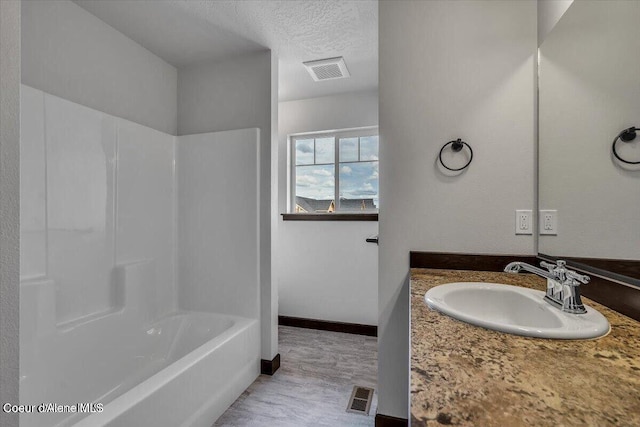 2711 E Cinder Ave, Post Falls, ID 83854 - full bathroom featuring a textured ceiling, bathtub / shower combination, baseboards, and vanity