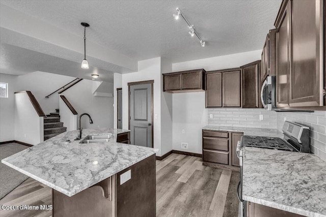 2711 E Cinder Ave, Post Falls, ID 83854 - kitchen featuring a sink, a textured ceiling, baseboards, appliances with stainless steel finishes, and tasteful backsplash