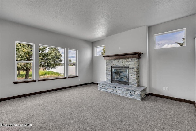 2711 E Cinder Ave, Post Falls, ID 83854 - unfurnished living room featuring a textured ceiling, carpet flooring, a stone fireplace, and baseboards