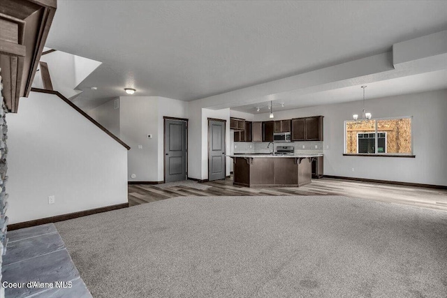 2711 E Cinder Ave, Post Falls, ID 83854 - unfurnished living room with baseboards, a chandelier, carpet flooring, and stairs