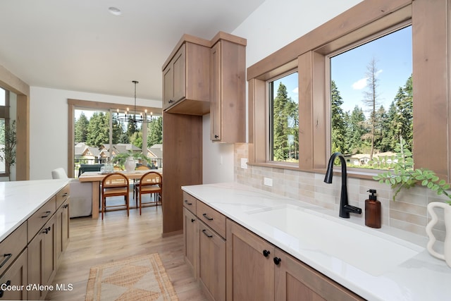 11996 N Rocking R, Hayden, ID 83835 - kitchen with light wood-type flooring, a chandelier, tasteful backsplash, light stone counters, and decorative light fixtures