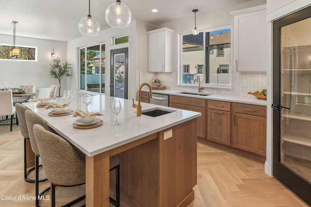 kitchen featuring tasteful backsplash, sink, an island with sink, and white cabinets