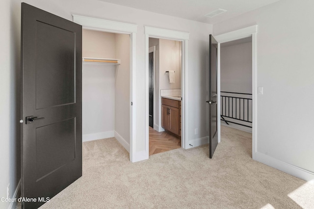 bedroom featuring connected bathroom, light colored carpet, and a closet