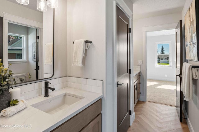 bathroom featuring vanity, parquet floors, and a textured ceiling