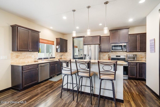 kitchen with dark hardwood / wood-style flooring, a kitchen island, stainless steel appliances, dark brown cabinetry, and decorative light fixtures